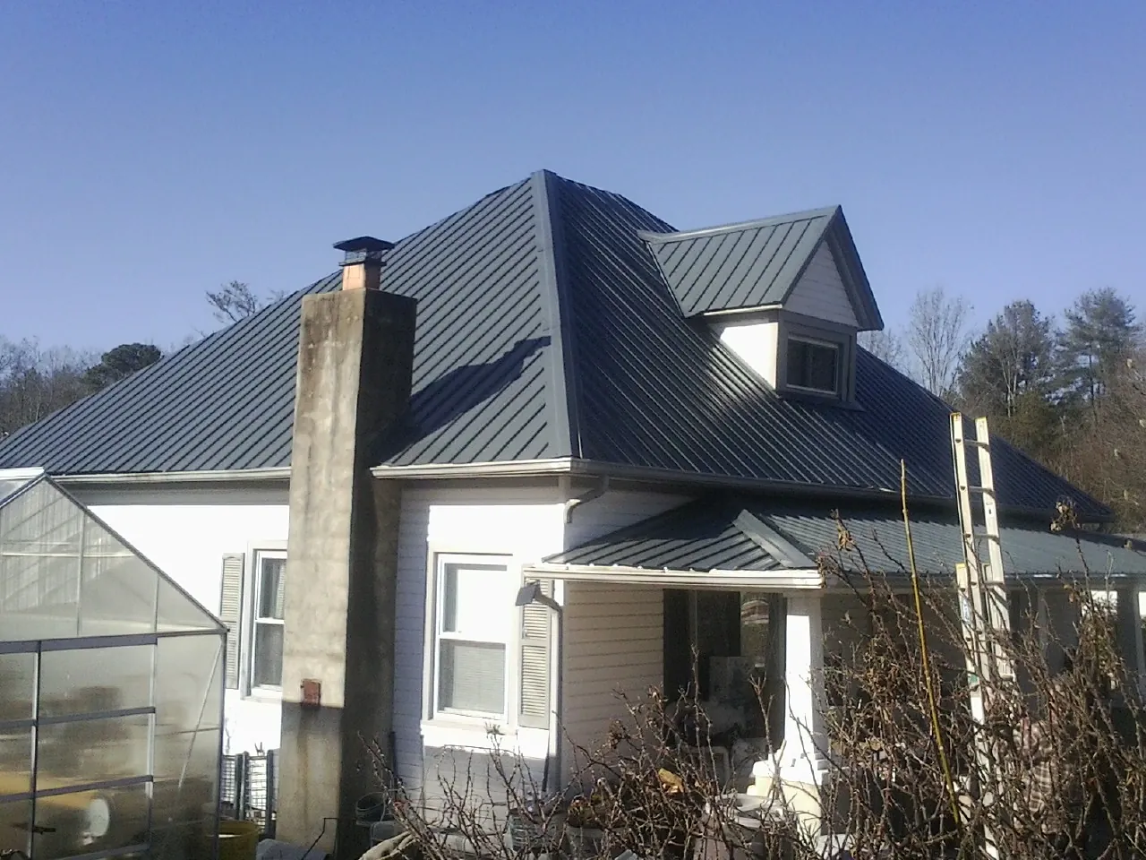 Dark blue standing seam metal roof on a white farmhouse with dormer — Slate & Tile Roof Repair by Roofing Brothers in Arena