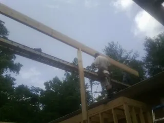 Carpenter setting a ridge beam over a new addition frame — Ice Dam Removal by Roofing Brothers in Arena
