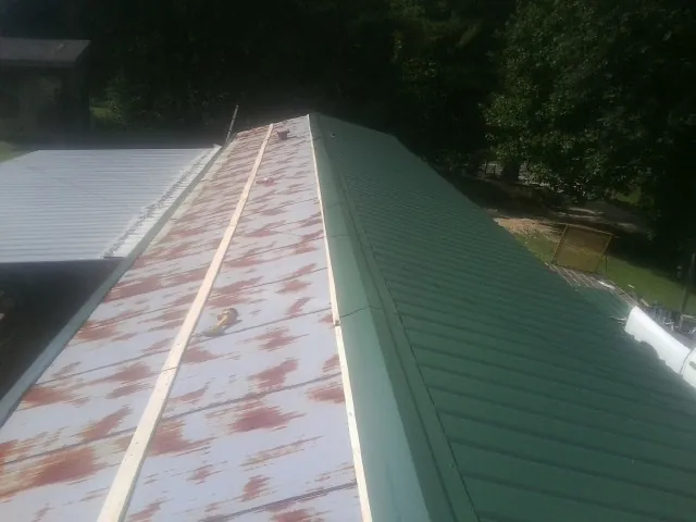 Old rusted panels beside newly installed green metal roofing — Wind Damage Roof Repair by Roofing Brothers in Arena