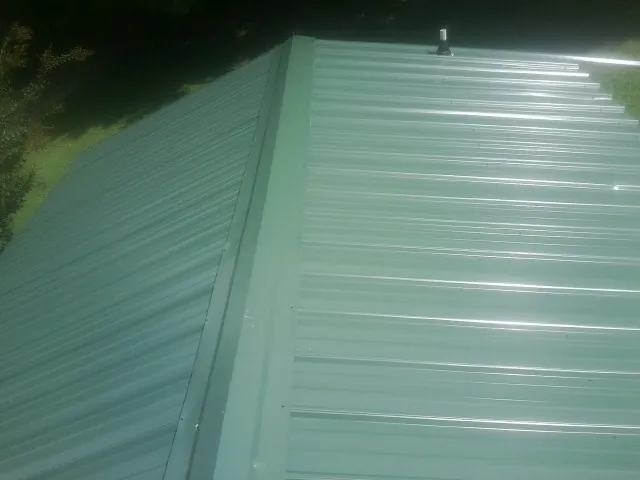 New green metal panels meeting at the ridge of a roof — Flat Roof Repair work by our crew in Arena