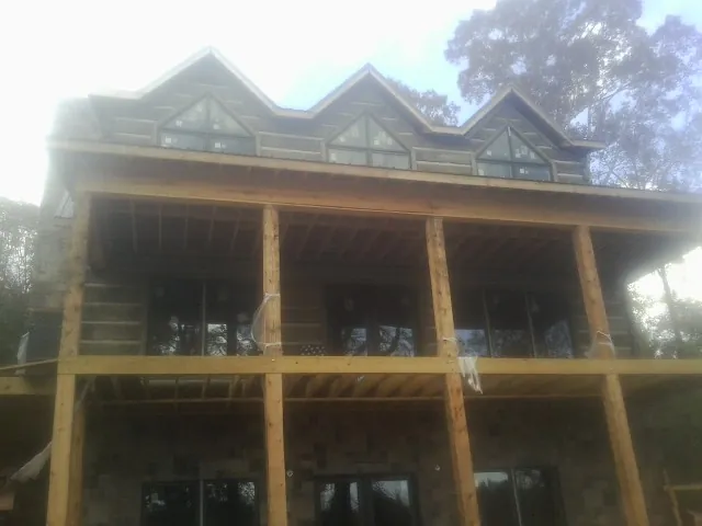Dormers and porch framing on a large log home under construction — Roof Coating work by our crew in Arena