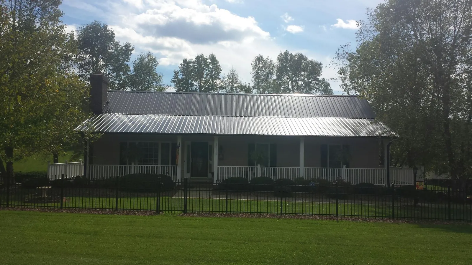Gray metal roof on a brick ranch with a full width front porch — Gutter Guard Installation work by our crew in Arena