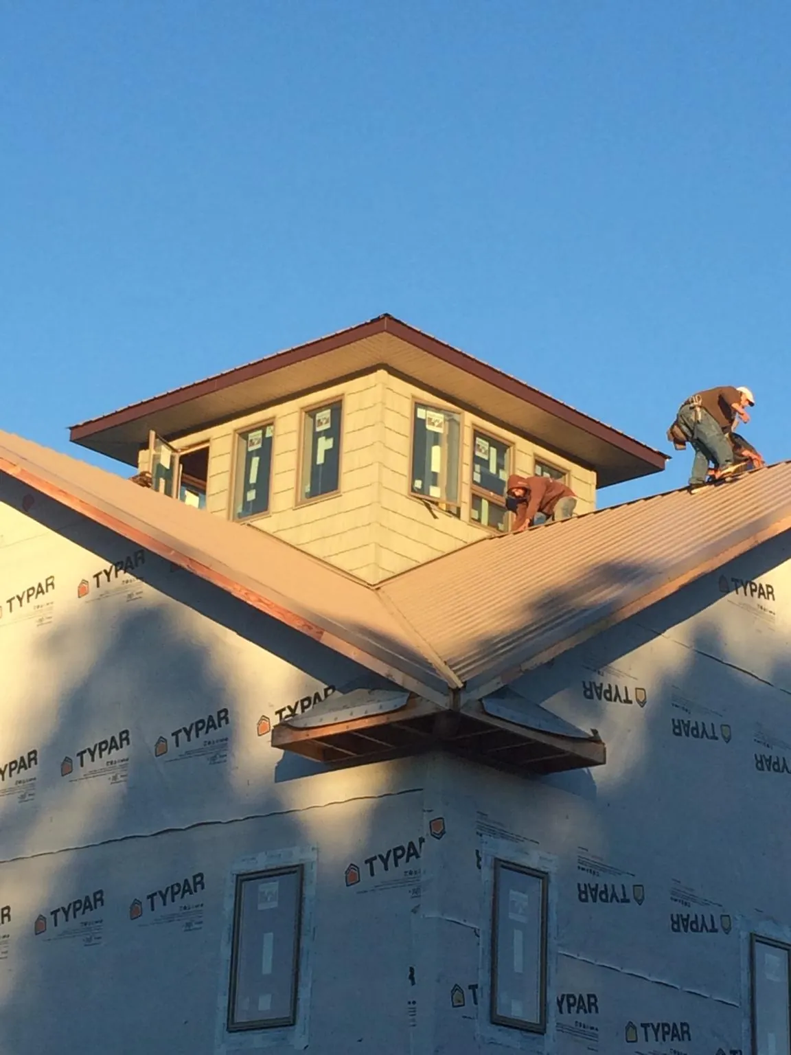 Roofers working around a rooftop cupola on a new metal roof at sunset — Roof Waterproofing in Arena by Roofing Brothers